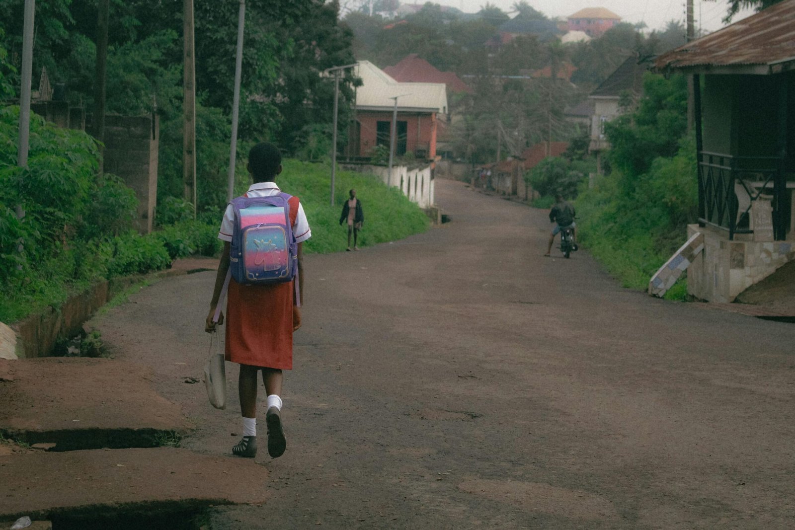 Child in school uniform walks on a calm street in Amechi, Nigeria.